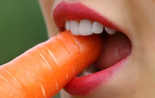 CAUSE E RIMEDI NATURALI PER PARODONTITE ragazza che mangia una carota