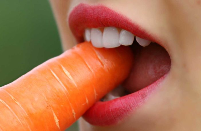 ragazza che mangia una carota